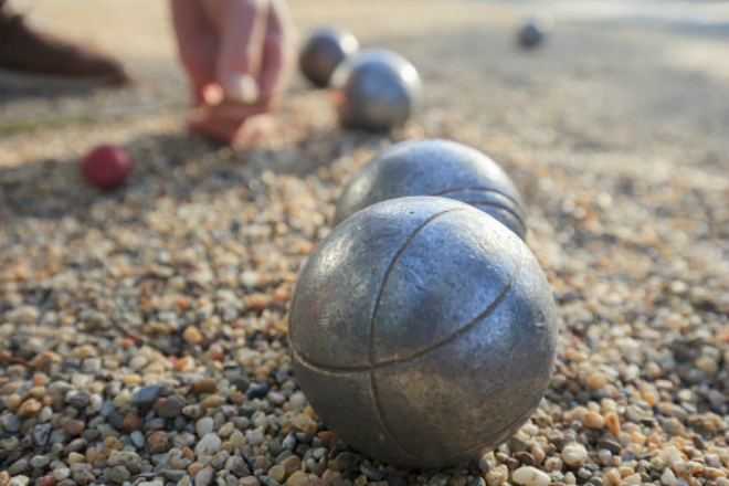 measuring the distance between metallic petanque balls and a small red jack on fine gravel