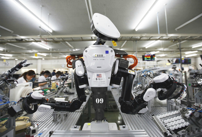 A humanoid robot works side by side with employees in the assembly line at a factory of Glory Ltd., a manufacturer of automatic change dispensers, in Kazo, north of Tokyo, Japan, in this July 1, 2015 file photo. Glory is in the vanguard as Japanese firms ramp up spending on robotics and automation, responding at last to premier Shinzo Abe's efforts to stimulate the economy and end two decades of stagnation and deflation. REUTERS/Issei Kato/Files