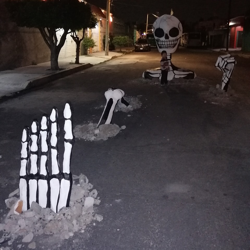 Vecinos tapan los baches de su colonia con calaveras gigantes y se hacen virales